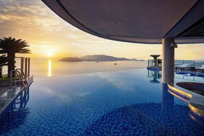 An infinity pool with a clear view of the sunset over the water, palm trees, and lounge chairs. - Best Western Premier Marvella Nha Trang (Nha Trang)