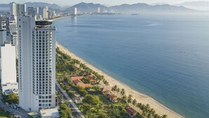 A coastal cityscape with a prominent white high-rise hotel, a beach, and distant mountains. - Best Western Premier Marvella Nha Trang (Nha Trang)