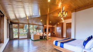A spacious room with a large bed, wooden flooring, and a balcony with a view of the outdoors. - DLS Serenity Resort And Spa (Manali)