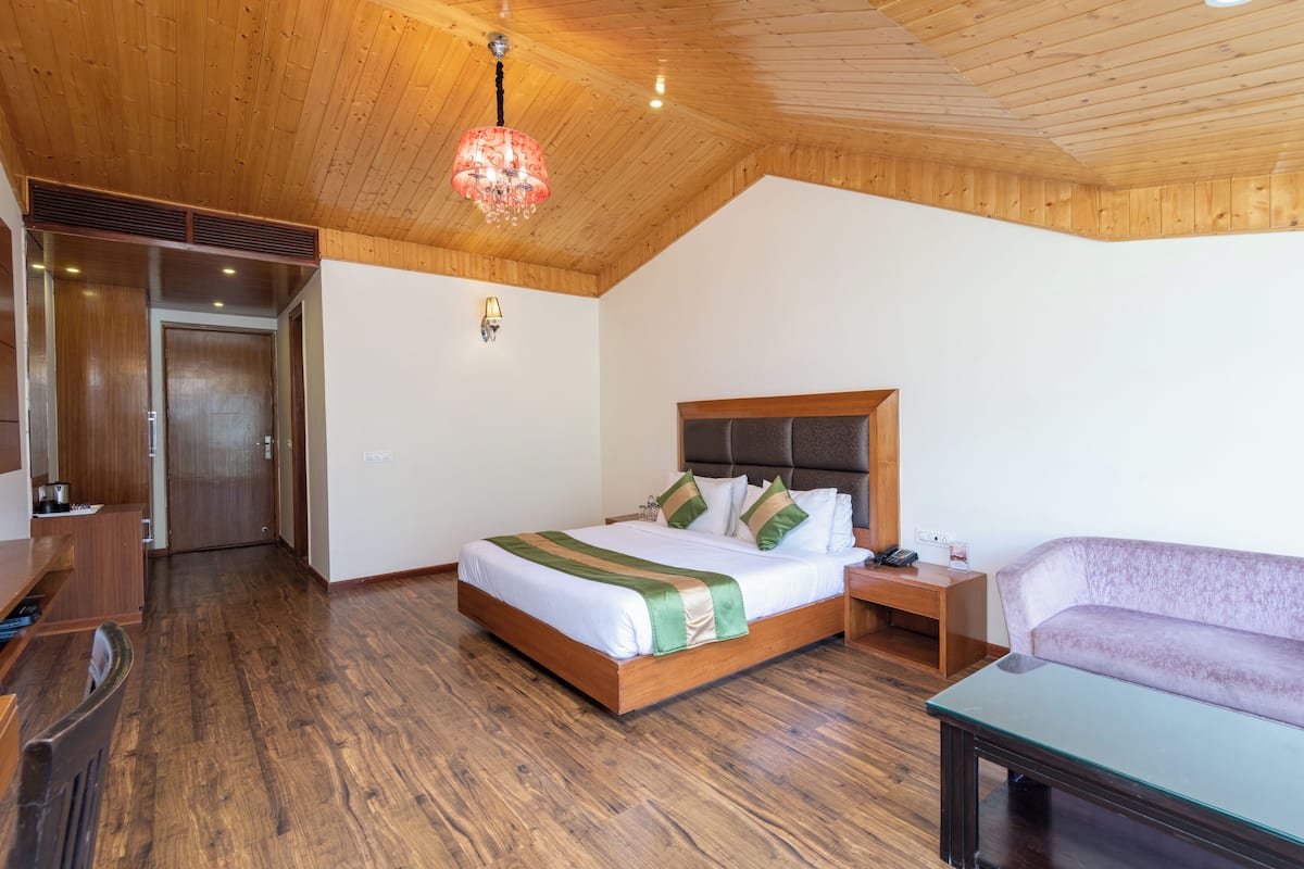 Ein Zimmer mit Holzwänden, einem Bett, einem Schlafsofa, einem Nachttisch und einem Tisch.
