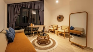 Una sala moderna con un sofá, sillas, una mesa redonda de centro y una zona de comedor con una mesa y sillas.