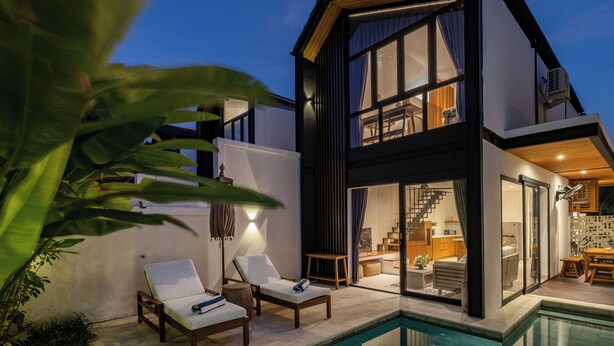 Una casa moderna de dos plantas con piscina, que cuenta con un amplio salón, una escalera y una cocina.
