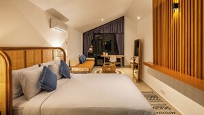 Una habitación de hotel moderna con una cama grande, un sofá, una mesita y un espejo.