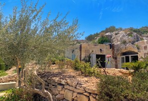 A stone-walled building with a rustic design, a tree in the foreground, and a clear blue sky.