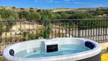 Un jacuzzi en un balcón con vistas a un paisaje montañoso.