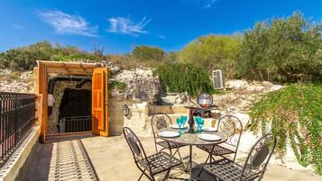 Un patio al aire libre con una mesa lista para comer, una parrilla y vistas del paisaje circundante.