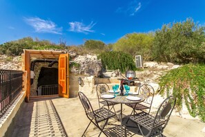 An outdoor patio with a table set for dining, a grill, and a view of the surrounding landscape.