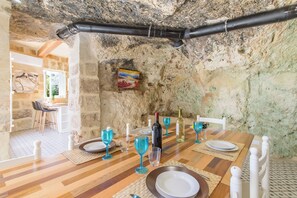 A rustic dining area with a stone wall, wooden table, and blue glassware.