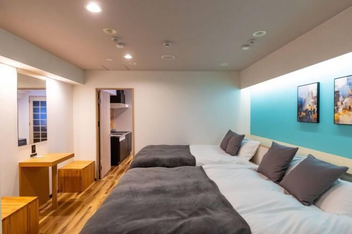 Habitación de hotel con piso de madera, un escritorio, dos camas y vista a la ciudad.