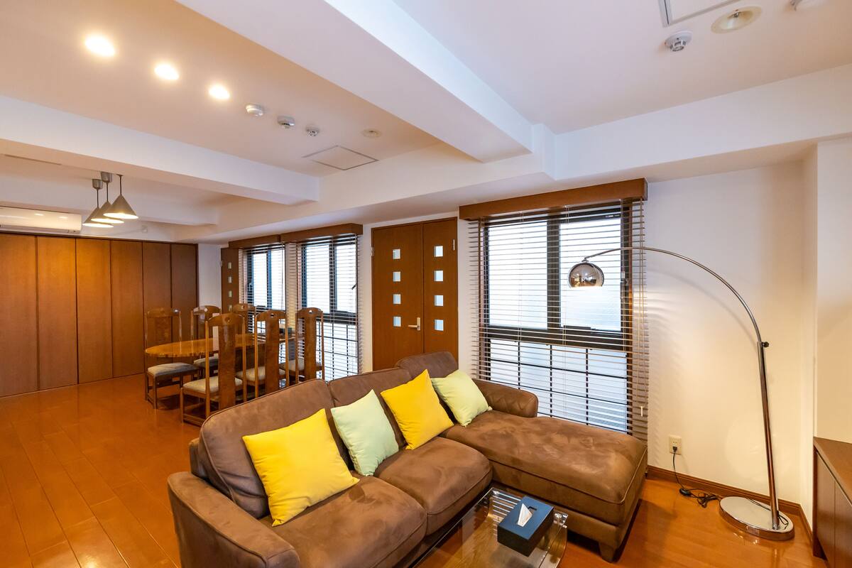 Una sala de estar moderna con un sofá seccional marrón, una mesa de comedor de madera y sillas.