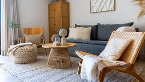 Ein Wohnzimmer mit einer Couch, zwei Sesseln, einem runden Couchtisch und einem Schrank.