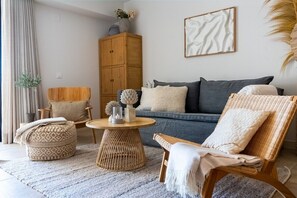 A living room with a sofa, two chairs, a round coffee table, and a cabinet.