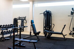 A gym with weightlifting equipment, a bench, and dumbbells.