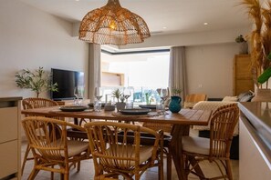 A dining area with a wooden table, wicker chairs, and a hanging light fixture.