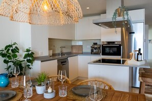 A modern kitchen with a central island, stainless steel appliances, and a hanging light fixture.
