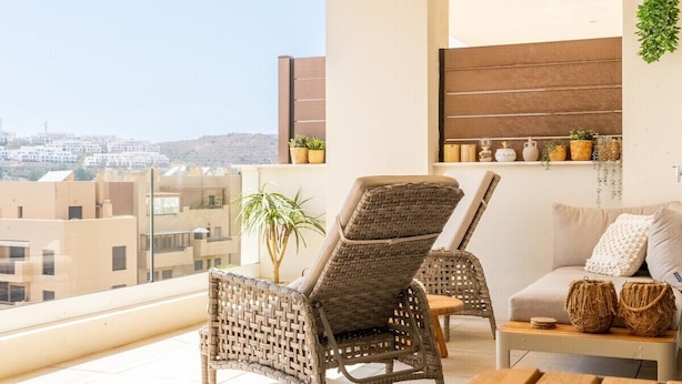 Ein Balkon mit Korbstühlen, einer Couch und einem kleinen Tisch mit Dekoration.