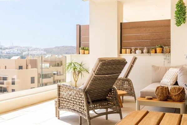 A balcony with wicker chairs, a sofa, and a small table with decorative items.