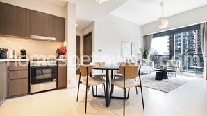 Una cucina moderna con elettrodomestici integrati, una zona pranzo con un tavolo rotondo e sedie, e vista sulla città attraverso ampie finestre.