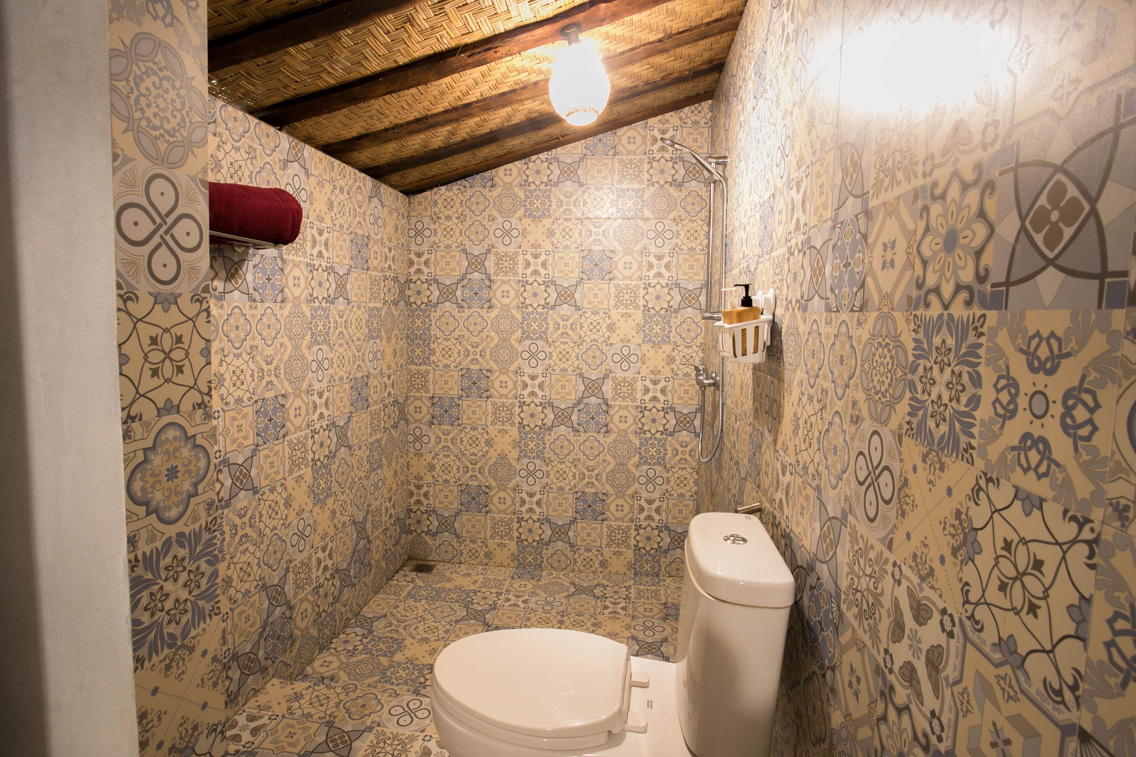 A bathroom with patterned tiles, a white toilet, and a shower area.
