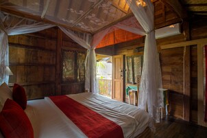 Una habitación de madera con una cama, una mesita y una puerta que da al exterior.