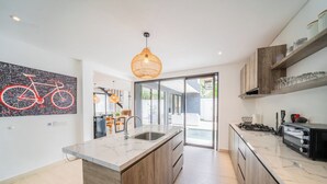 Uma cozinha moderna com uma ilha grande, armários de madeira e um espaço de refeições com arte inspirada em bicicletas.