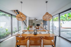 Enjoy meals in this stylish dining area with a large table and comfortable chairs, surrounded by beautiful garden views.