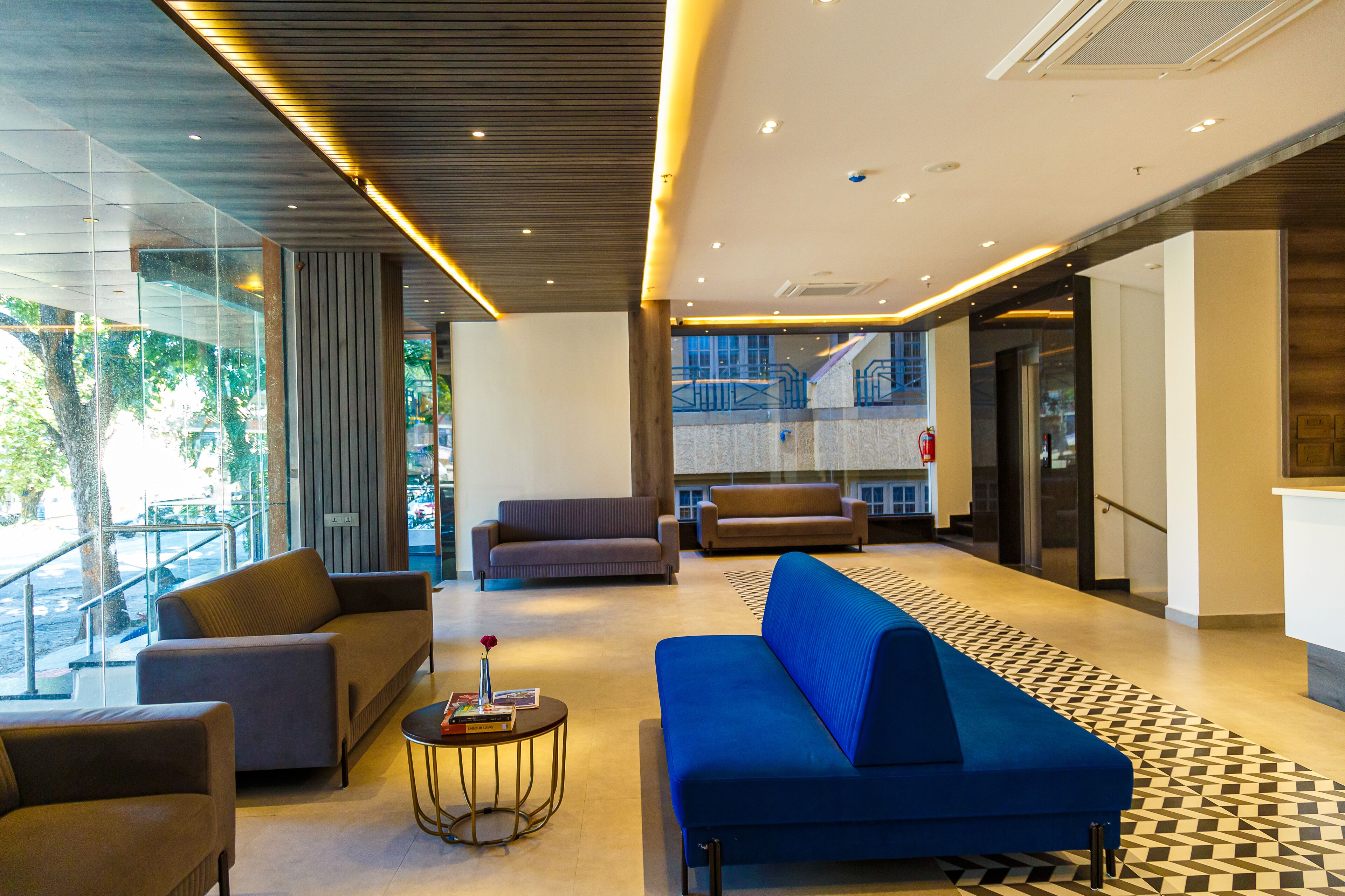 A modern lobby with sofas, a coffee table, and a staircase.