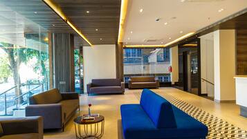 A modern lobby with sofas, a coffee table, and a staircase.