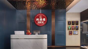 A reception desk with a laptop, a decorative fruit bowl, and a red circular sign with Chinese characters.