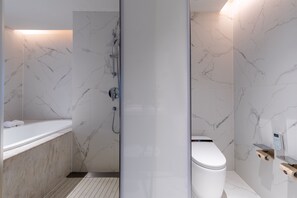 Ein modernes Badezimmer mit Duschkabine aus Marmor, einer Badewanne und einer Toilette.