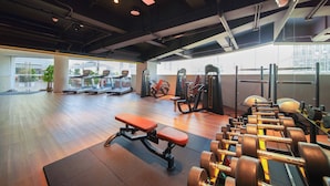 A gym with exercise equipment, benches, and dumbbells.