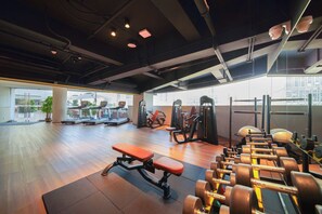 Een sportschool met trainingsapparatuur, banken en gewichten.