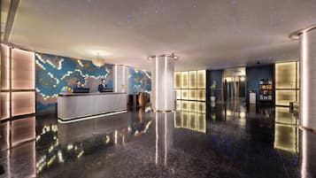 A hotel lobby with a reception desk, a patterned wall, a column, and a polished floor.