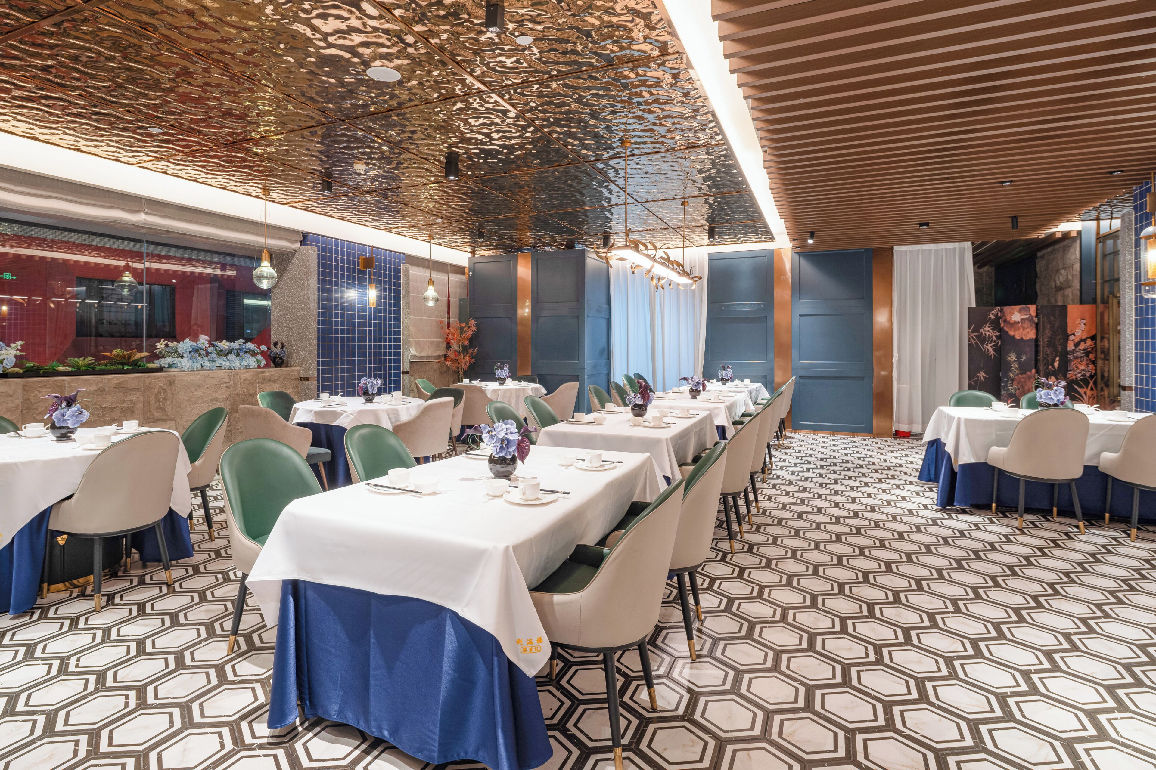 A restaurant with multiple tables set for dining, featuring a patterned floor and a ceiling with a unique design.
