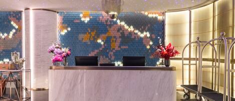 A reception area with a marble counter, two chairs, and a decorative wall with a mosaic pattern.