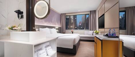 Une chambre d’hôtel avec un grand lit, une table de chevet, une salle de bain avec un lavabo et un miroir, et une vue sur le paysage urbain.