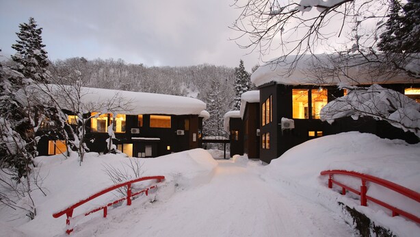 A snow-covered pathway leading to a building with a red railing. - Alpine Tenshi Villa (Hakuba)