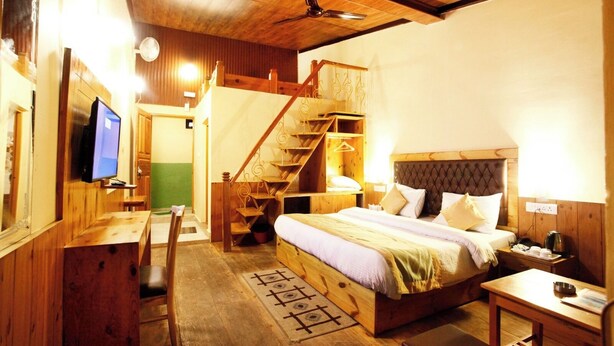 Ein gemütlicher Holzraum mit Bett, Schreibtisch, Fernseher und einer Treppe.