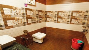 Ein Badezimmer mit Toilette, Waschbecken mit Marmorplatte und einem roten Eimer.
