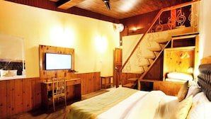Ein gemütliches Zimmer mit Bett, Schreibtisch, Fernseher und einer Treppe.