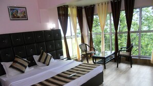 Ein Hotelzimmer mit einem großen Bett, einem kleinen Tisch, zwei Stühlen und einem Fenster mit Vorhängen.