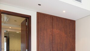 A wooden wardrobe in a room with white walls and a ceiling vent. - HomesGetaway- 1BR in JLT Lake Views (Dubai)