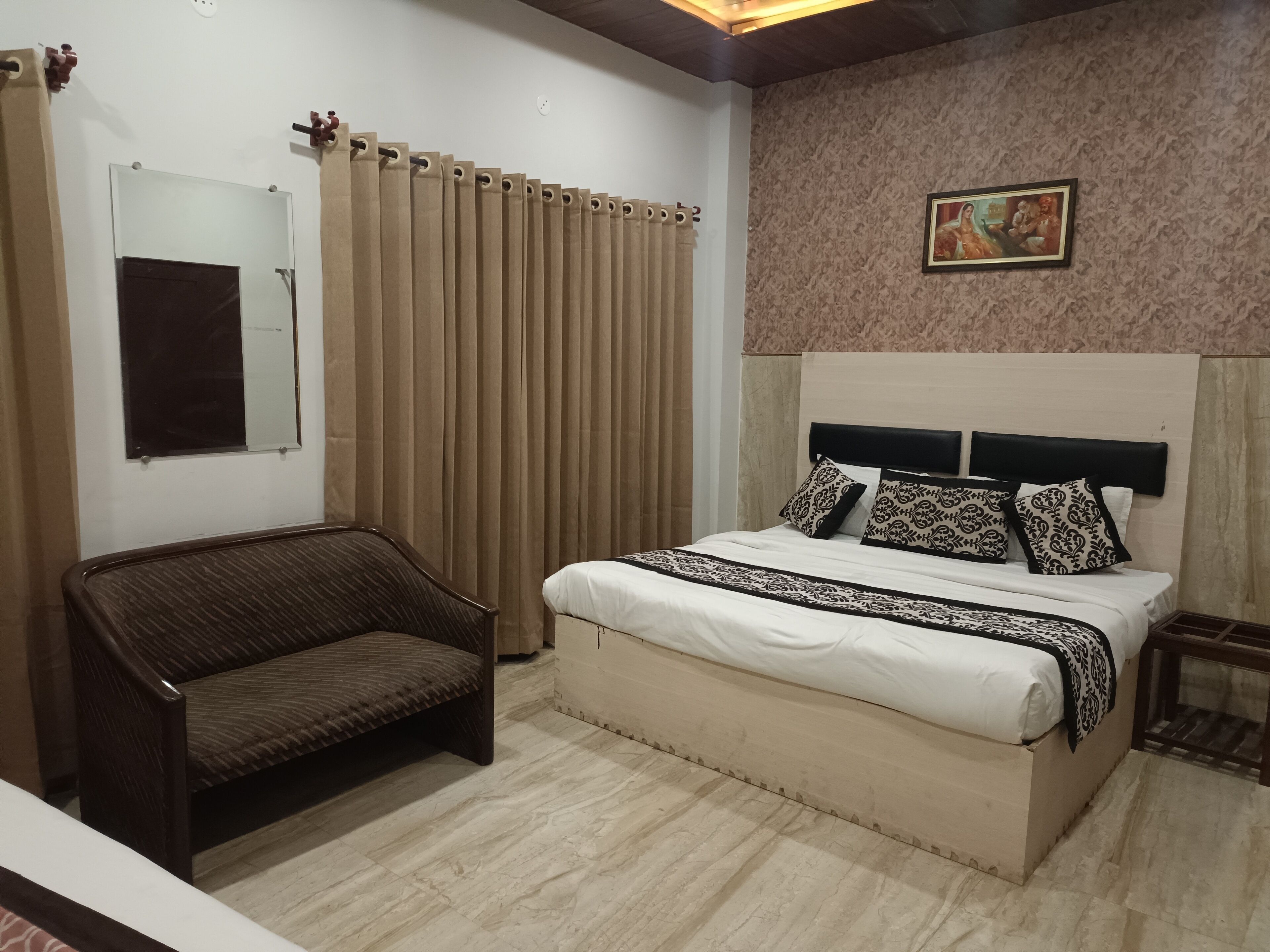 A bedroom with a bed, a chair, a mirror, and a painting on the wall.