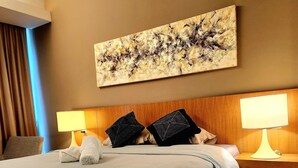 Una camera d'albergo con un letto grande, due lampade sui comodini, una testiera e un quadro appeso al muro.