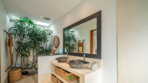 Ein modernes Badezimmer mit einem großen Spiegel, zwei Waschtüben und einer Topfpflanze.
