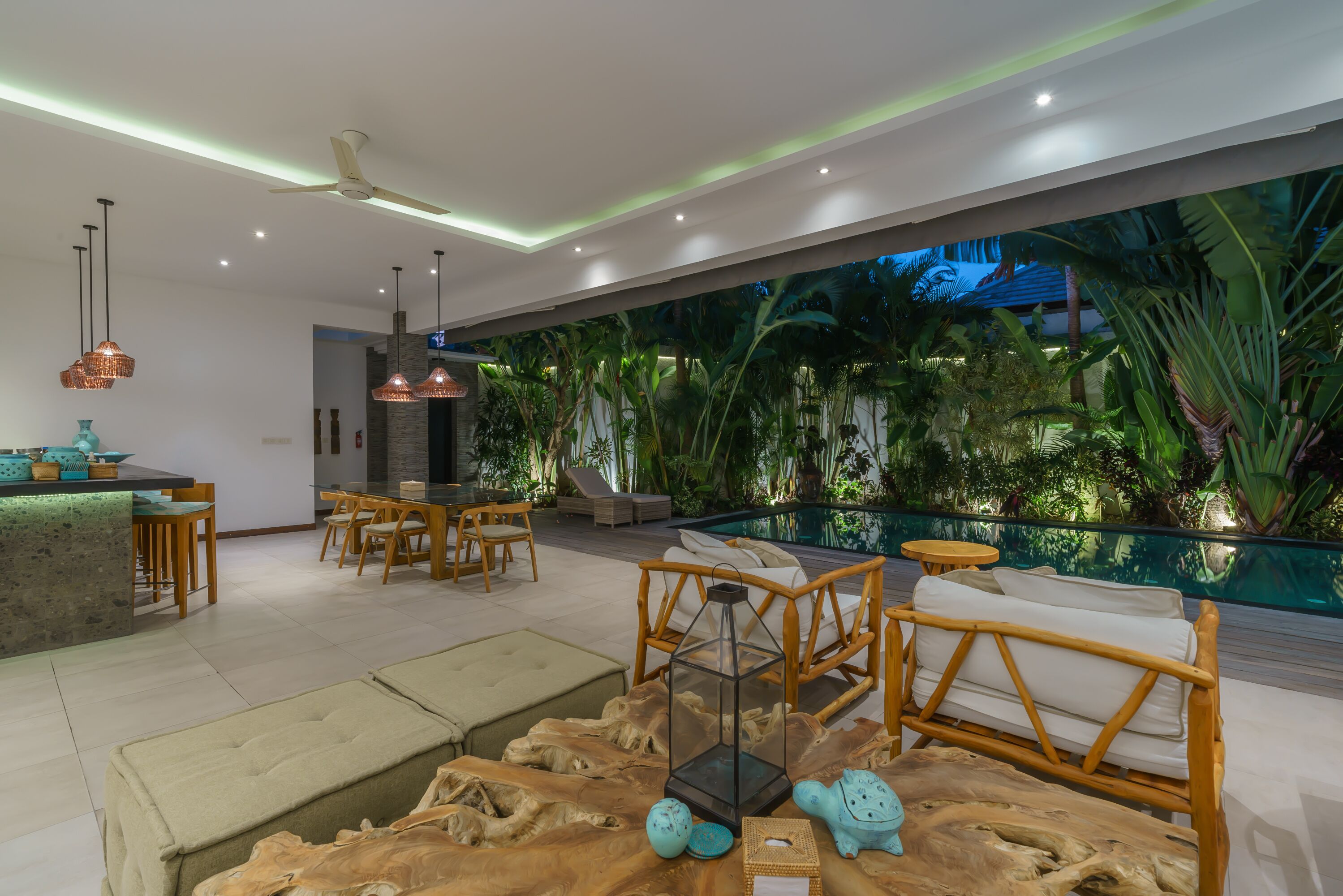 A modern interior with a dining area, seating, and a poolside view.