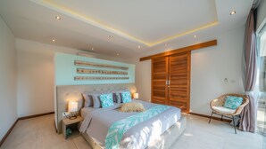 Ein modernes Schlafzimmer mit einem großen Bett, einem Holzschrank, einem Korbstuhl und einem an der Wand befestigten Kunstwerk.