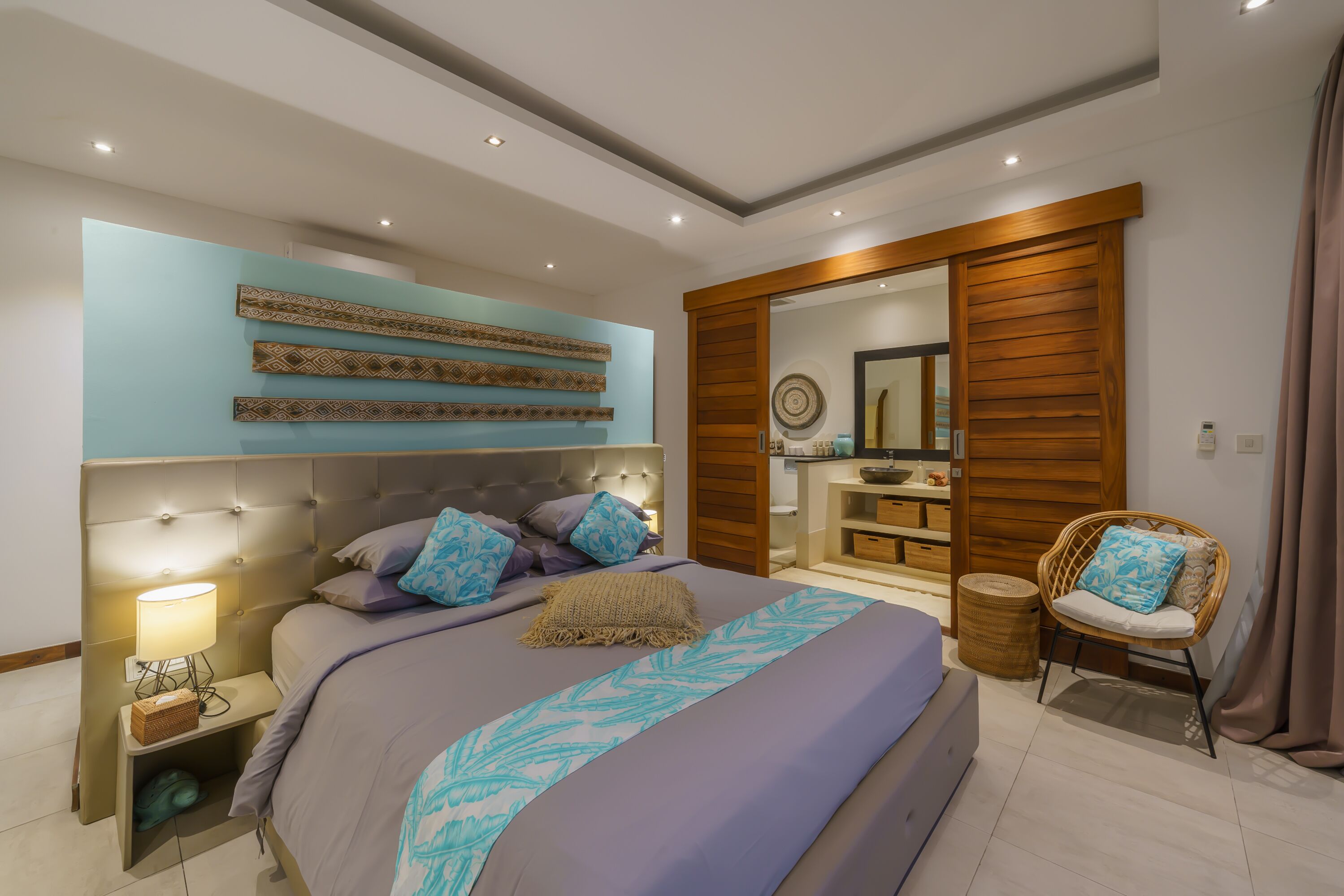 Ein modernes Schlafzimmer mit einem großen Bett, einem Nachttisch, einem Sessel und einem Holzschrank.