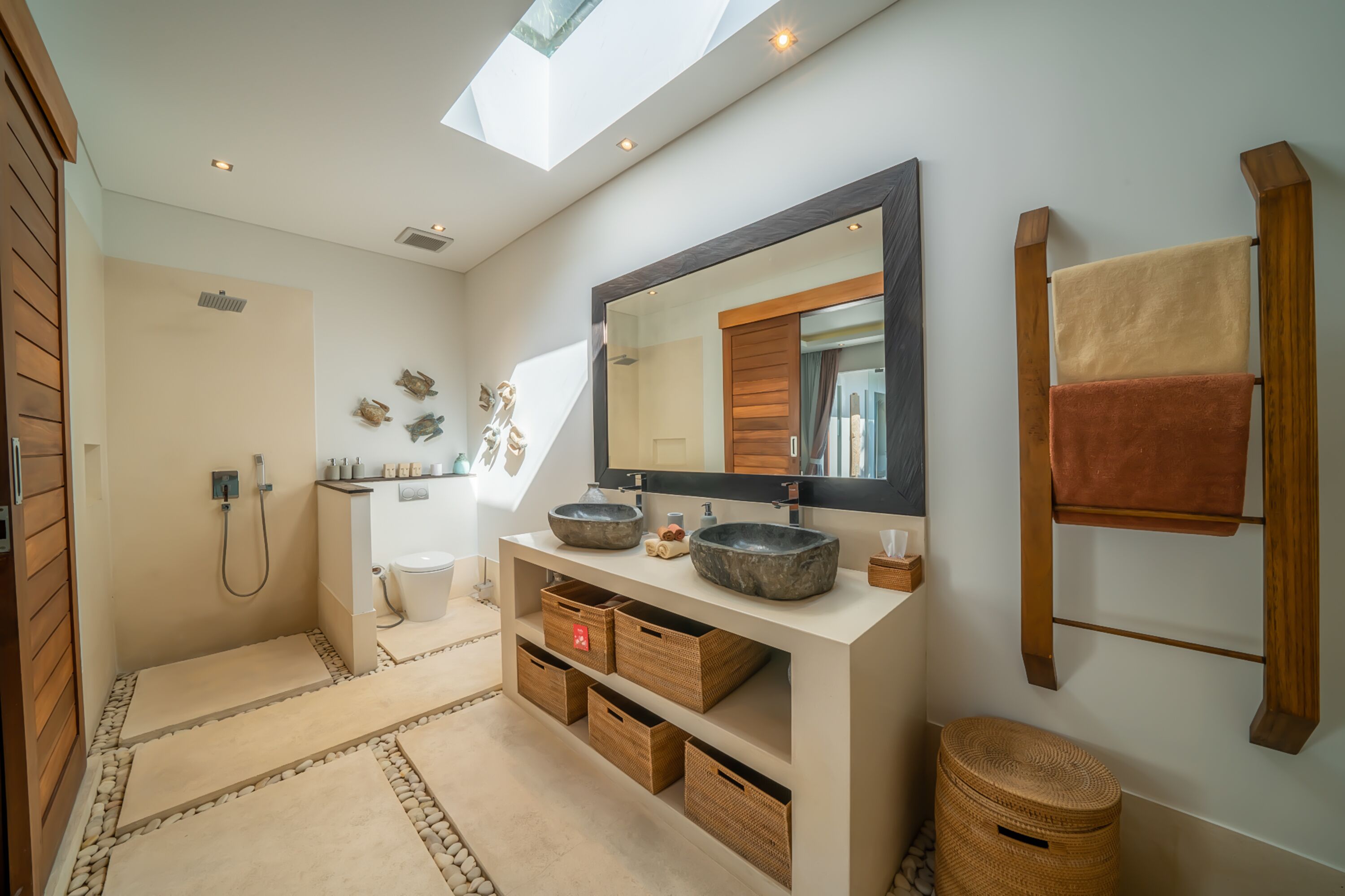 A modern bathroom with a skylight, large mirror, and built-in storage.