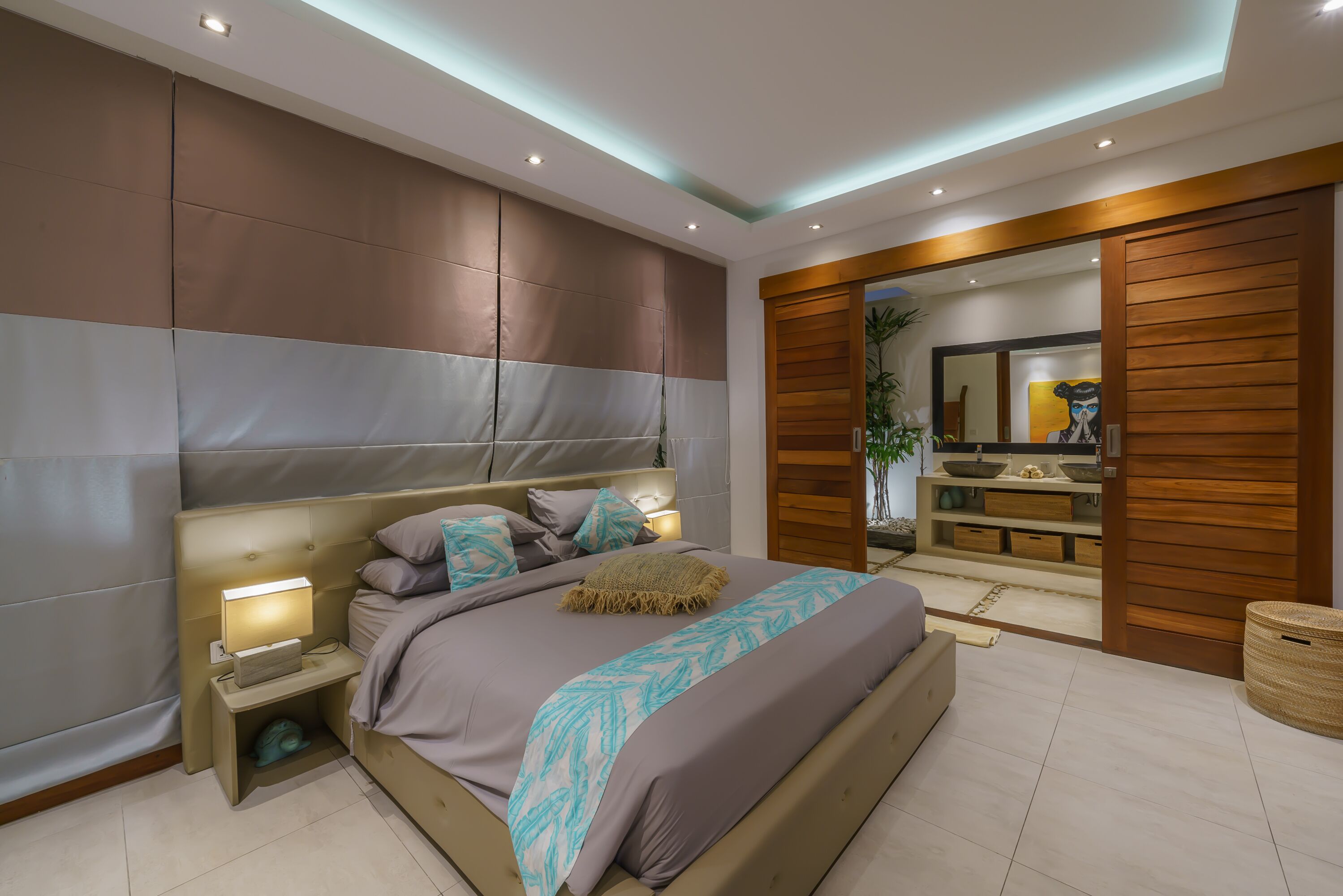 Ein modernes Schlafzimmer mit einem großen Bett, Nachttischlampen, einem Holzschrank und einem Badezimmer mit Holztür und Regalen.